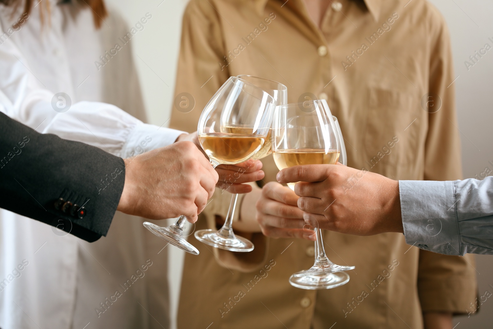 Photo of People clinking glasses of wine indoors, closeup