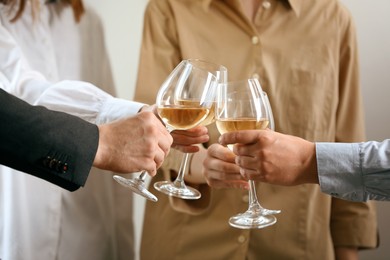 People clinking glasses of wine indoors, closeup