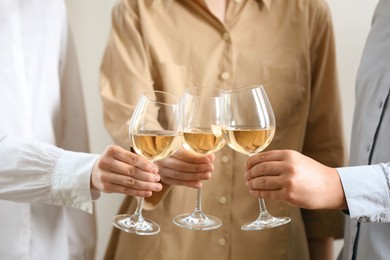 People clinking glasses of wine indoors, closeup