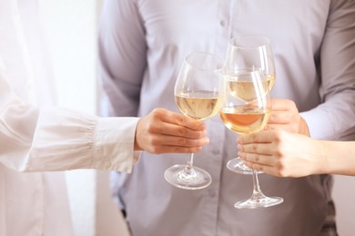 Photo of People clinking glasses of wine indoors, closeup