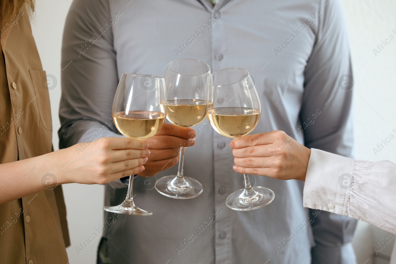 Photo of People clinking glasses of wine indoors, closeup