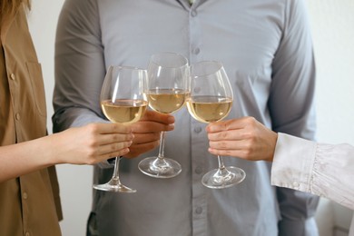 Photo of People clinking glasses of wine indoors, closeup