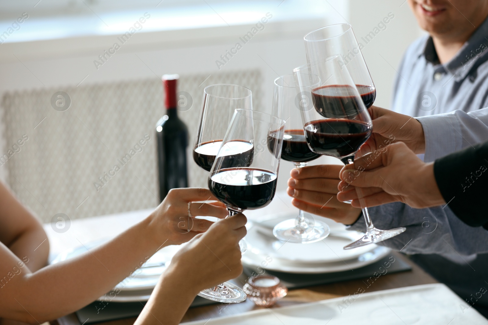 Photo of People clinking glasses of wine indoors, closeup