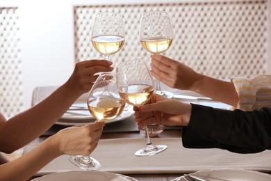 Photo of People clinking glasses of wine indoors, closeup