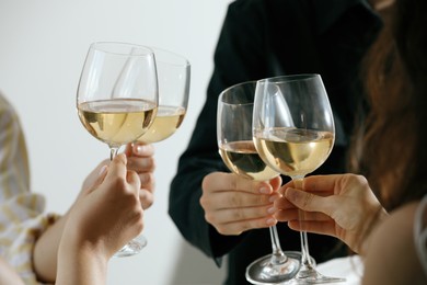 Photo of People clinking glasses of wine indoors, closeup