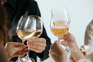 Photo of People clinking glasses of wine indoors, closeup