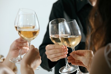 Photo of People clinking glasses of wine indoors, closeup