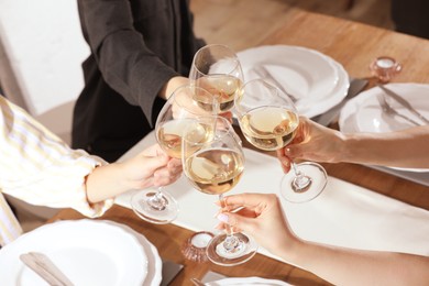 Photo of People clinking glasses of wine indoors, closeup