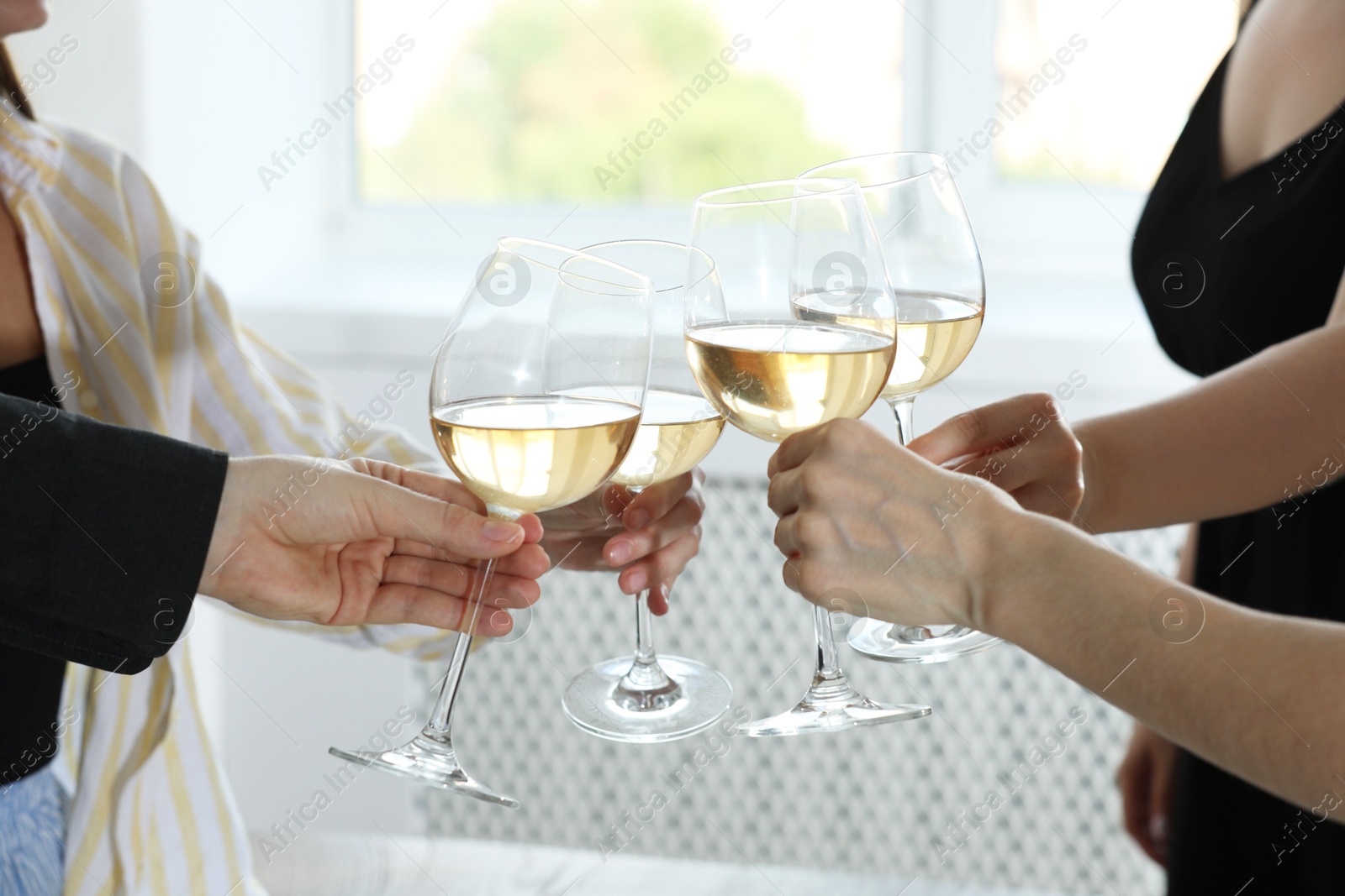 Photo of People clinking glasses of wine indoors, closeup