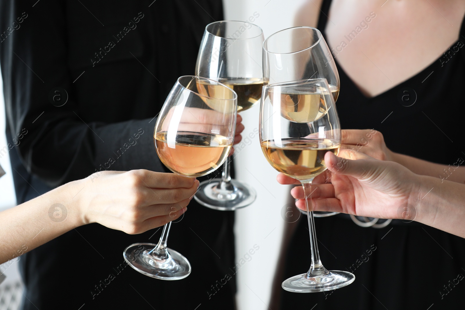 Photo of People clinking glasses of wine indoors, closeup