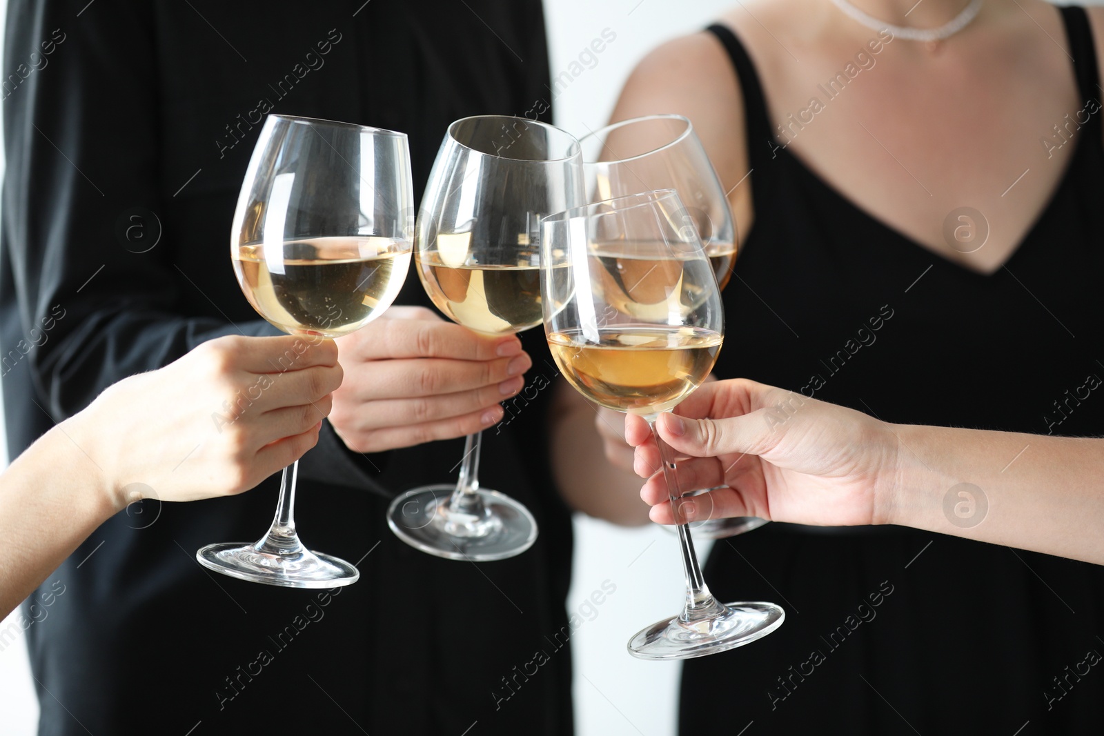 Photo of People clinking glasses of wine indoors, closeup