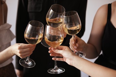 Photo of People clinking glasses of wine indoors, closeup