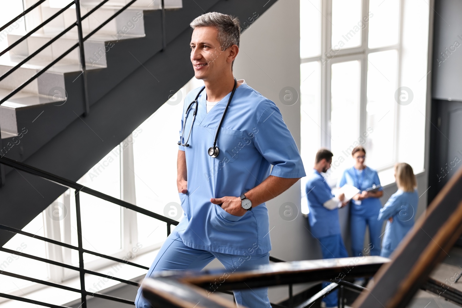 Photo of Smiling healthcare worker with stethoscope walking up stairs in hospital