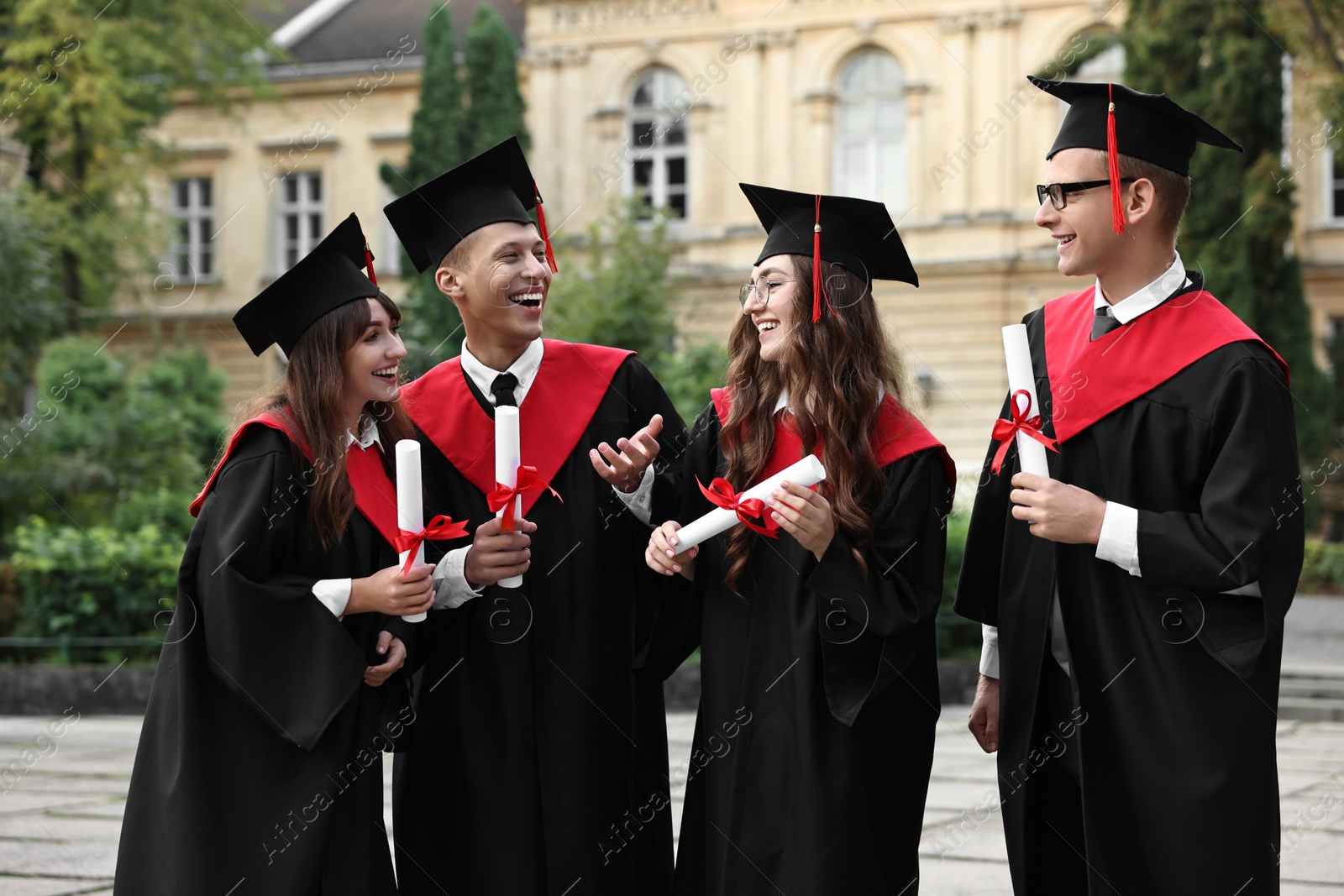 Photo of Happy students with diplomas after graduation ceremony outdoors