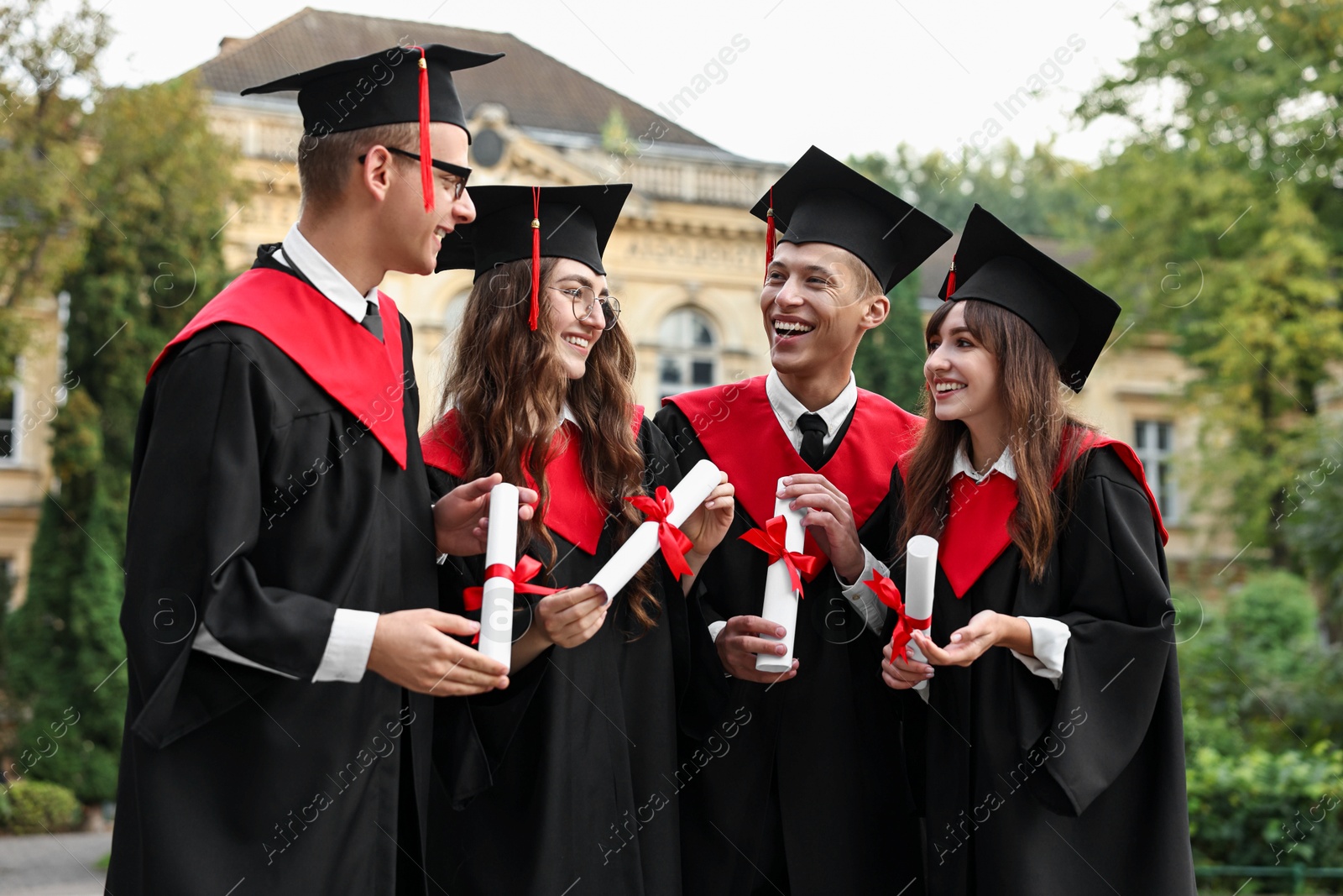 Photo of Happy students with diplomas after graduation ceremony outdoors