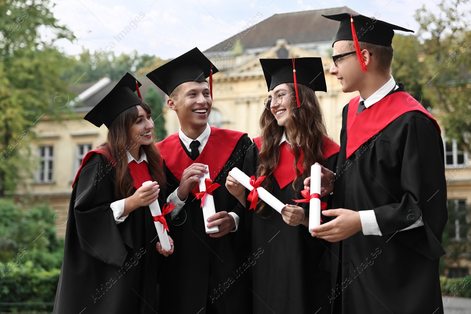 Photo of Happy students with diplomas after graduation ceremony outdoors