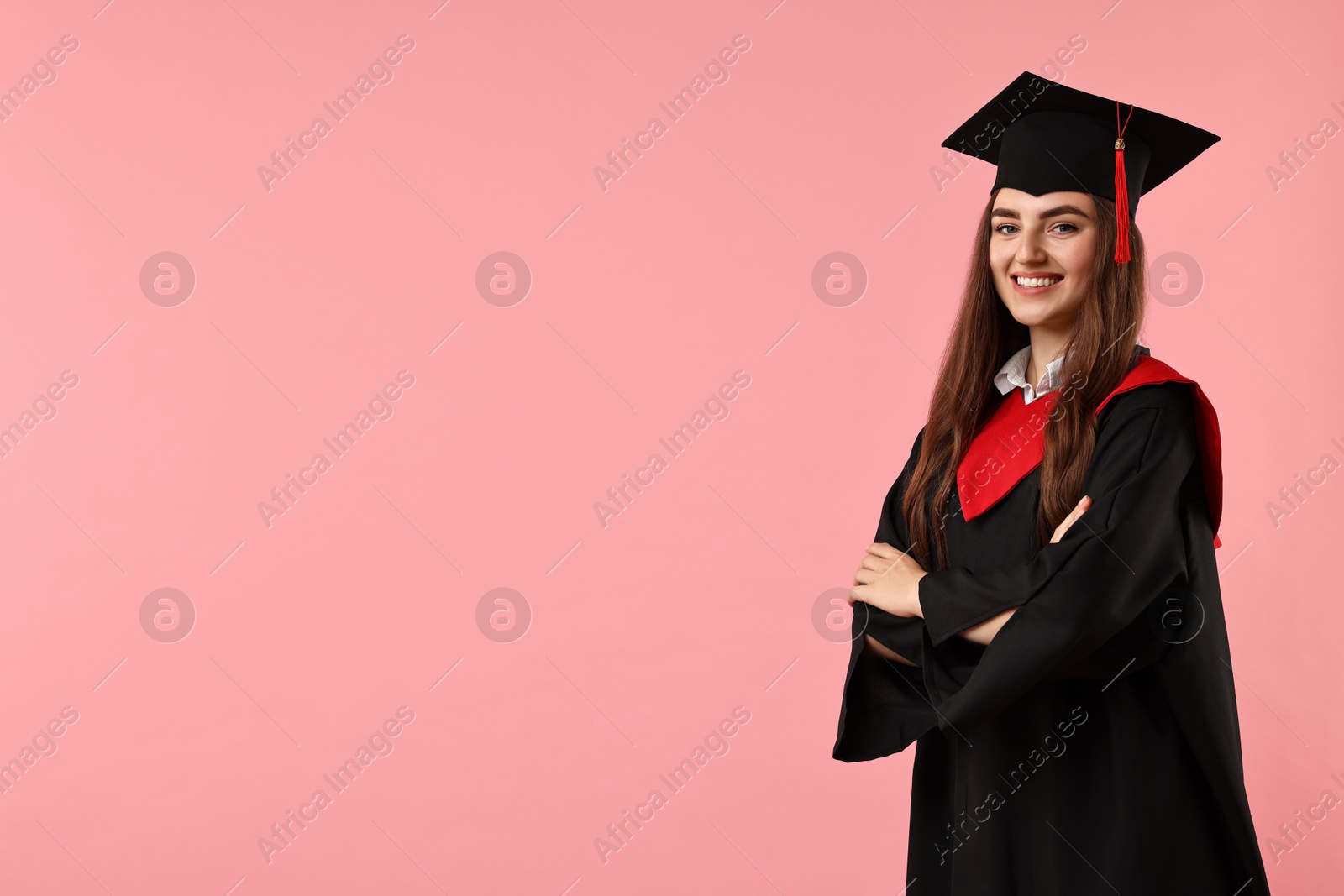 Photo of Happy student with crossed arms after graduation on pink background. Space for text