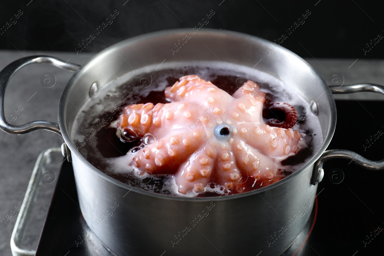 Photo of Fresh octopus boiling in pan on stove, closeup