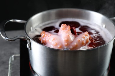 Photo of Fresh octopus boiling in pan on stove, closeup