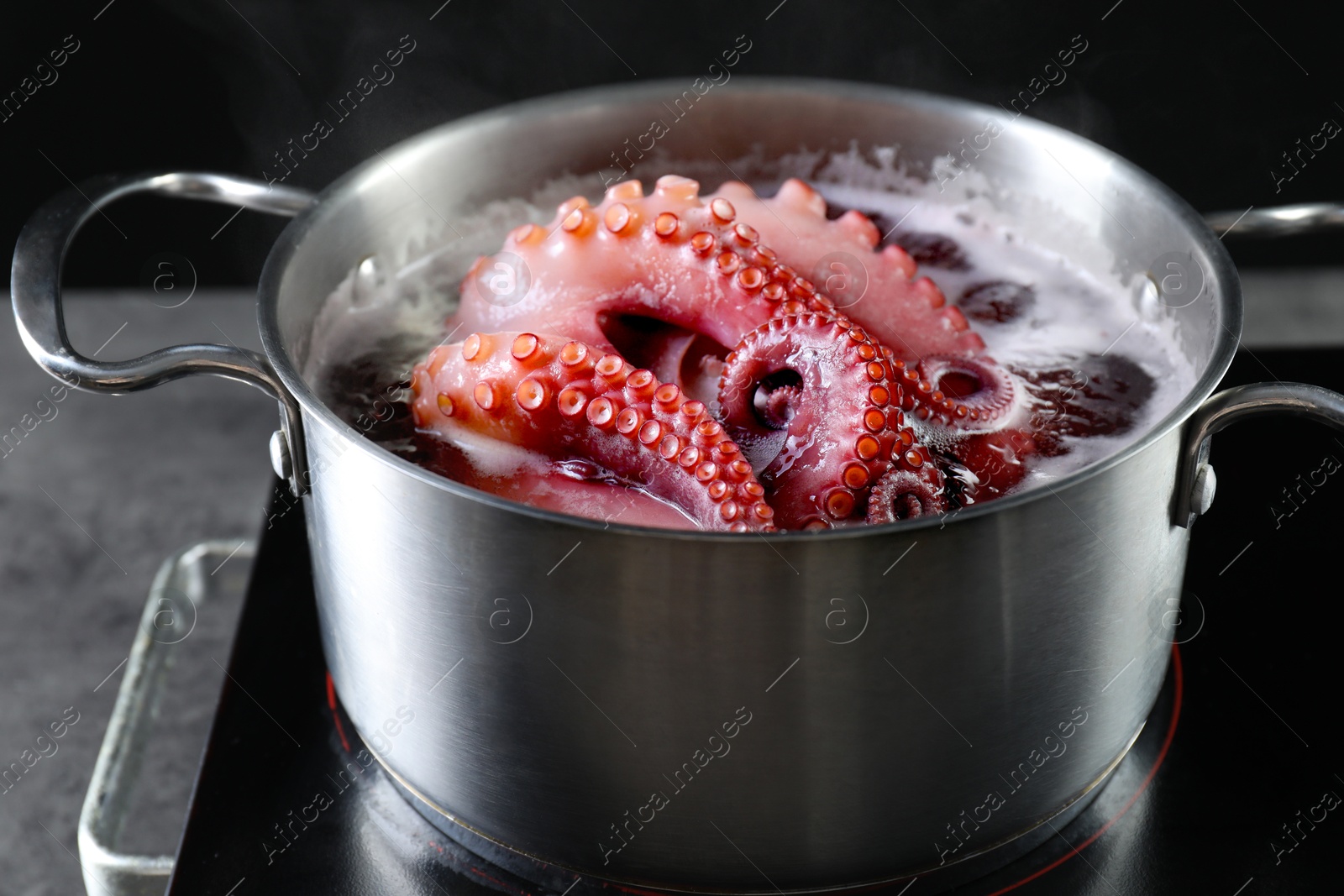 Photo of Fresh octopus boiling in pan on stove, closeup