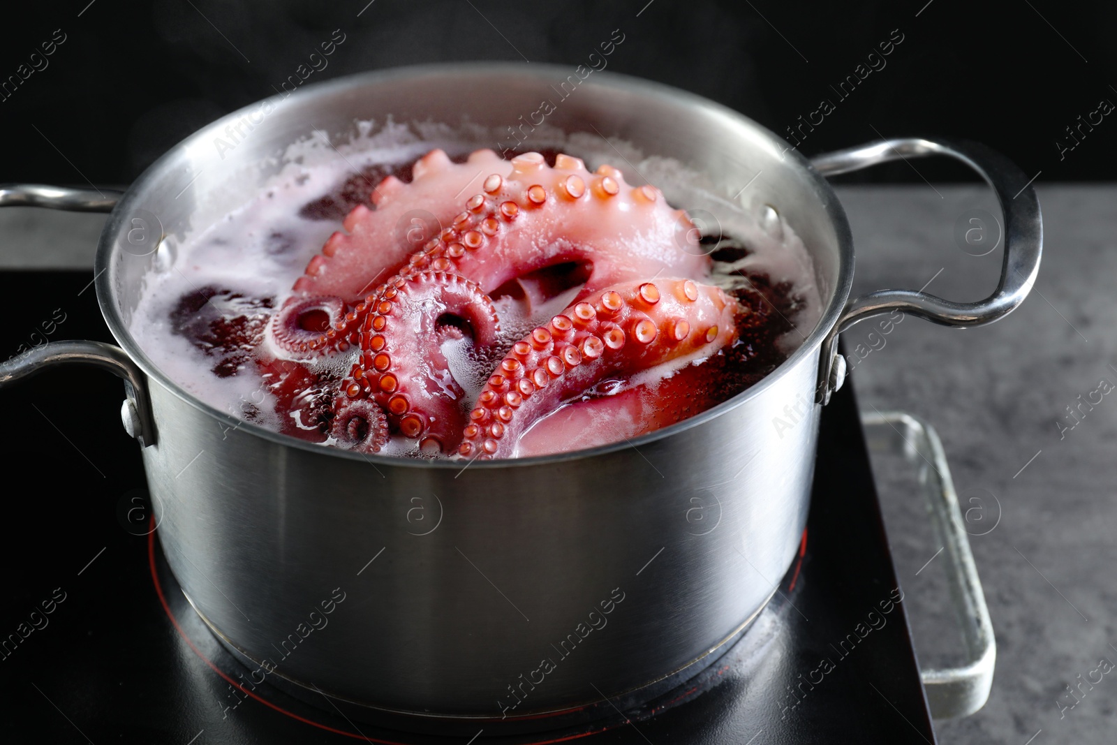 Photo of Fresh octopus boiling in pan on stove, closeup