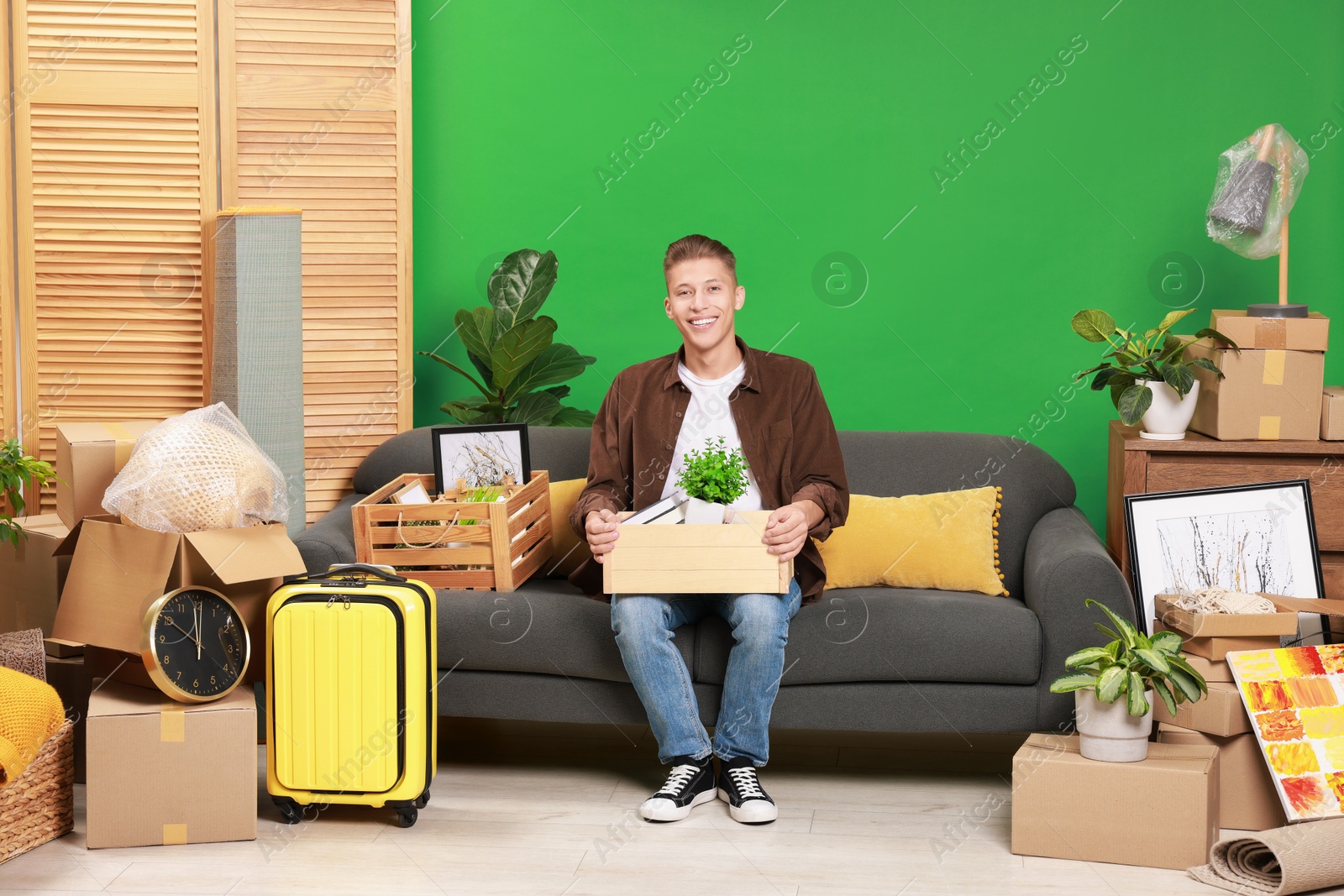 Photo of Happy man with different stuff in new apartment. Housewarming party