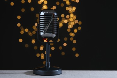 Photo of Vintage microphone on table against black background with blurred lights. Sound recording and reinforcement