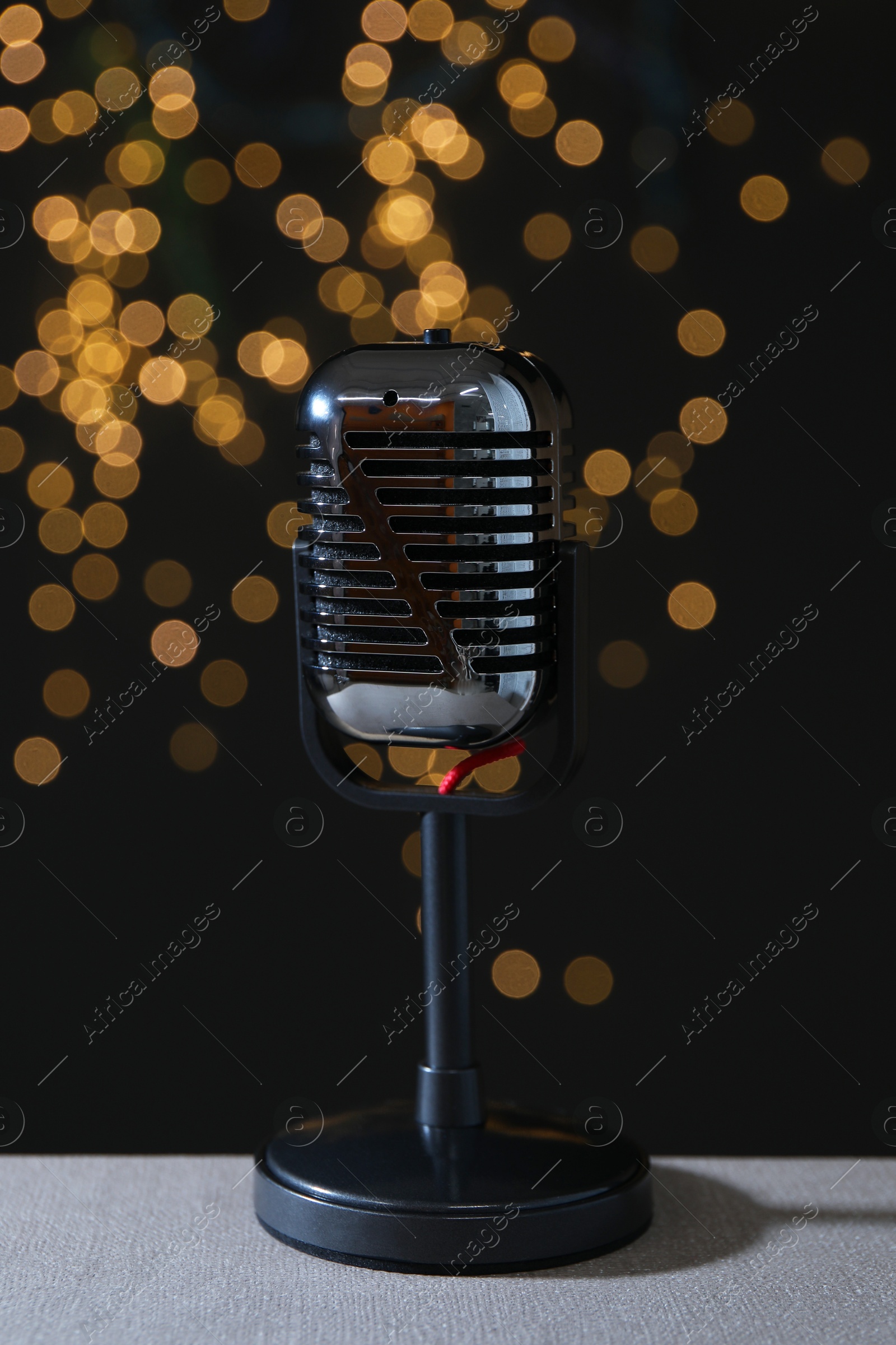 Photo of Vintage microphone on table against black background with blurred lights. Sound recording and reinforcement