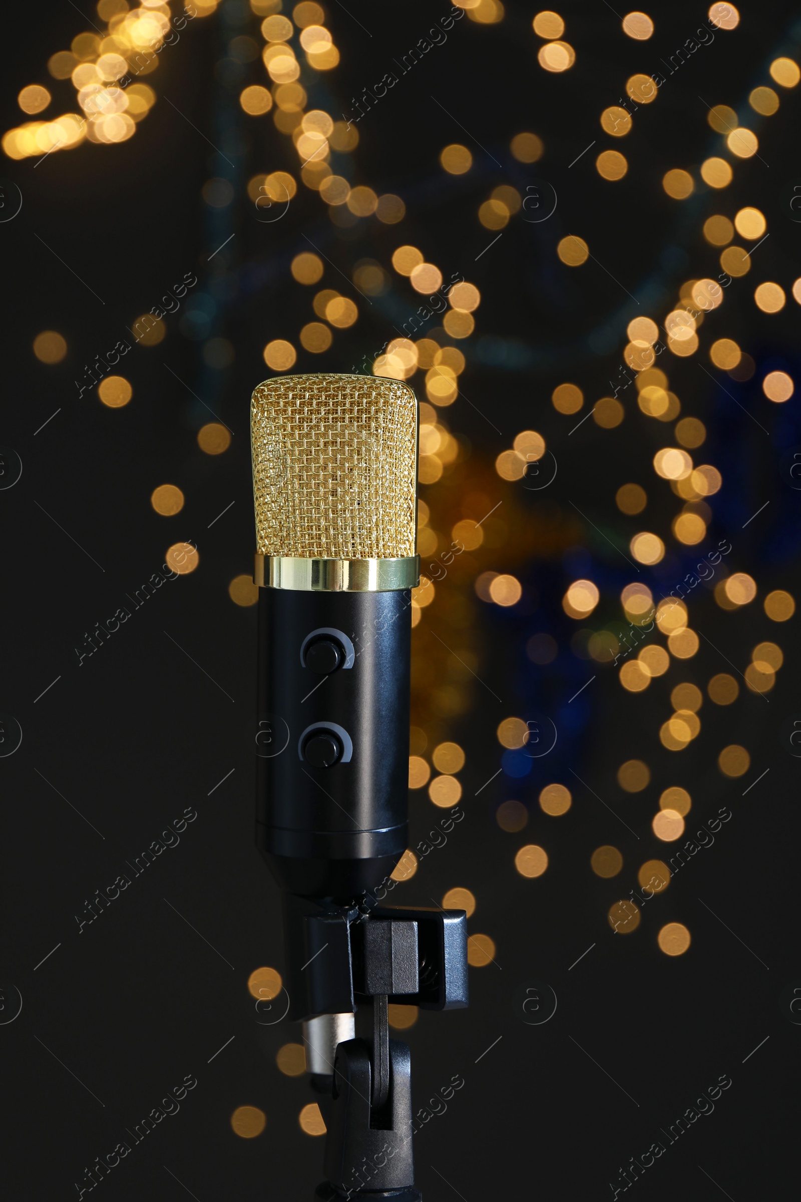 Photo of Microphone against dark grey background with blurred lights. Sound recording and reinforcement