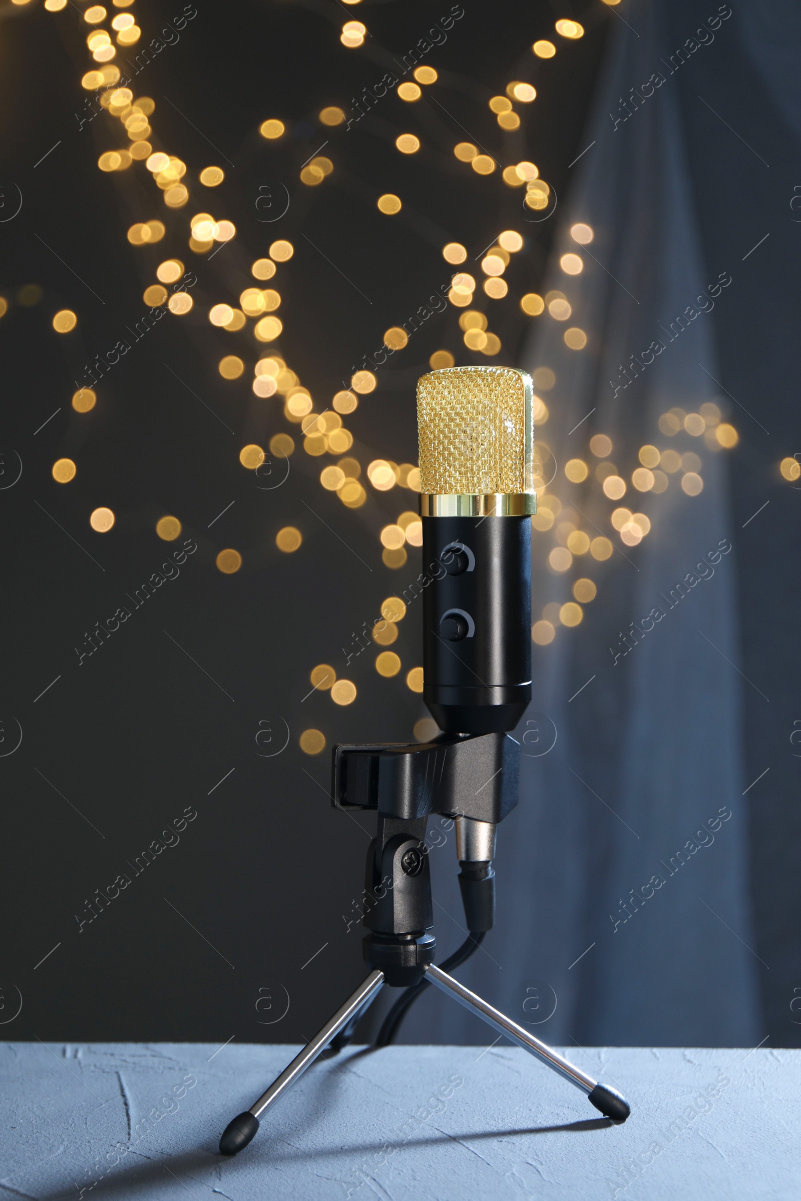 Photo of Microphone on table against dark grey background with blurred lights. Sound recording and reinforcement