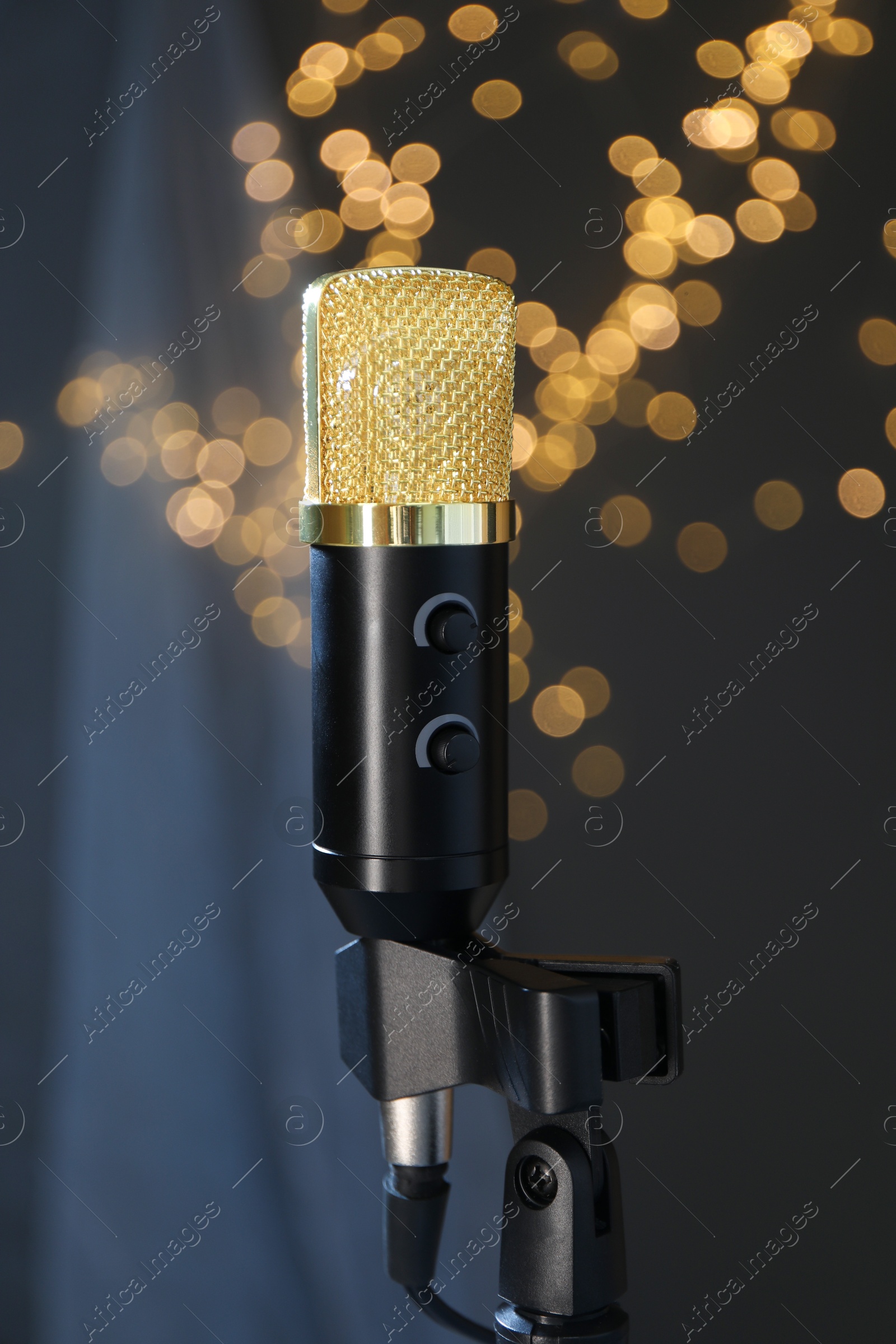 Photo of Microphone against dark grey background with blurred lights. Sound recording and reinforcement