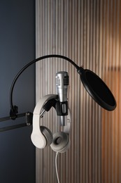 Photo of Stand with microphone, headphones and pop filter indoors. Sound recording and reinforcement