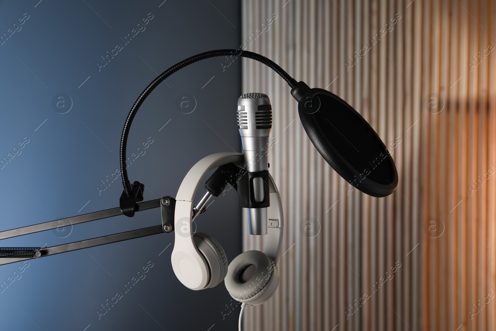 Photo of Stand with microphone, headphones and pop filter indoors. Sound recording and reinforcement