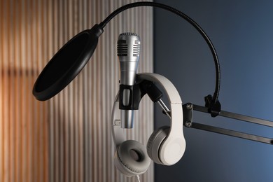 Photo of Stand with microphone, headphones and pop filter indoors. Sound recording and reinforcement