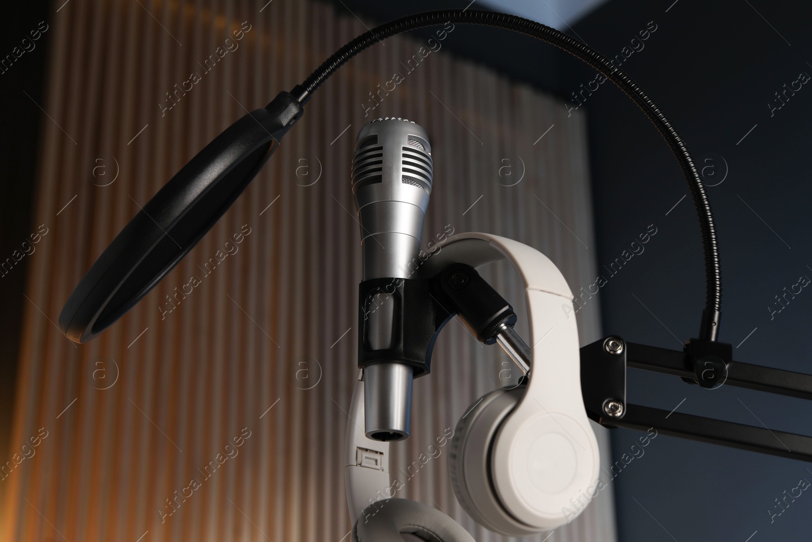 Photo of Stand with microphone, headphones and pop filter indoors, low angle view. Sound recording and reinforcement