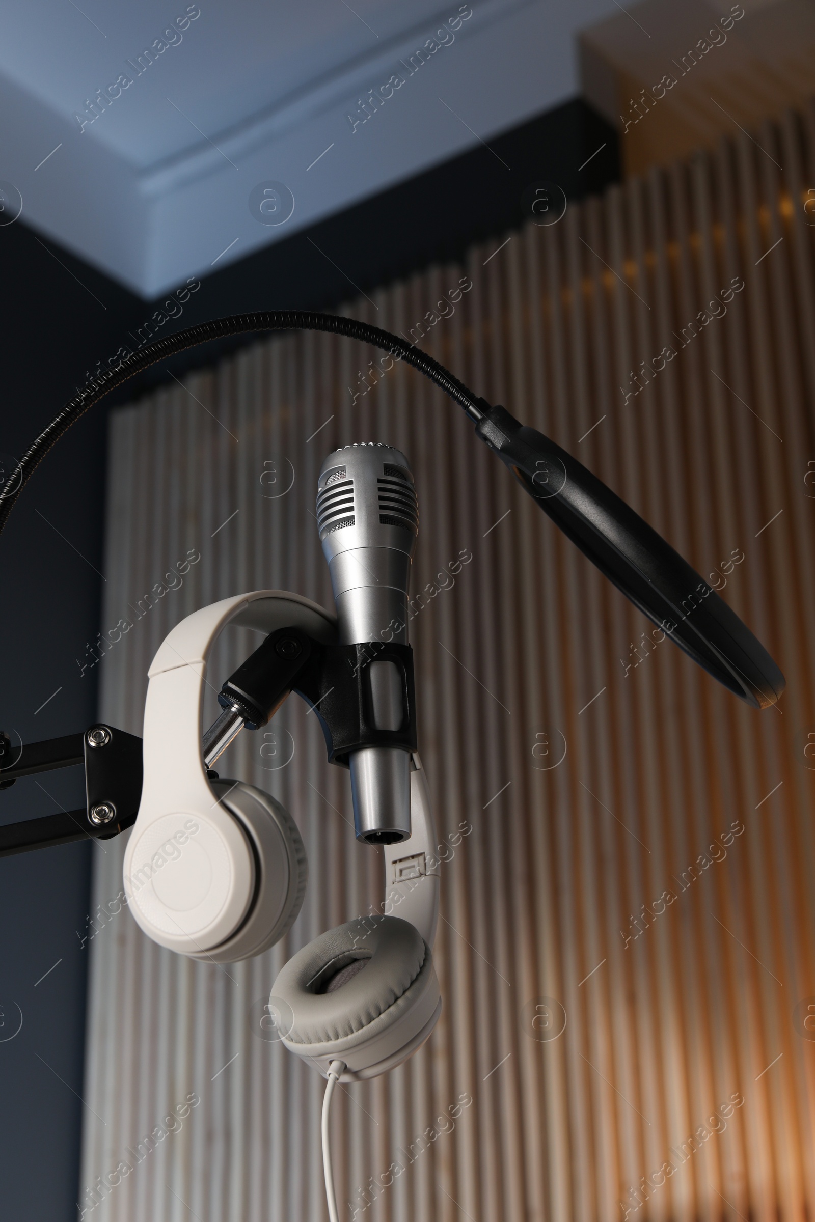 Photo of Stand with microphone, headphones and pop filter indoors, low angle view. Sound recording and reinforcement