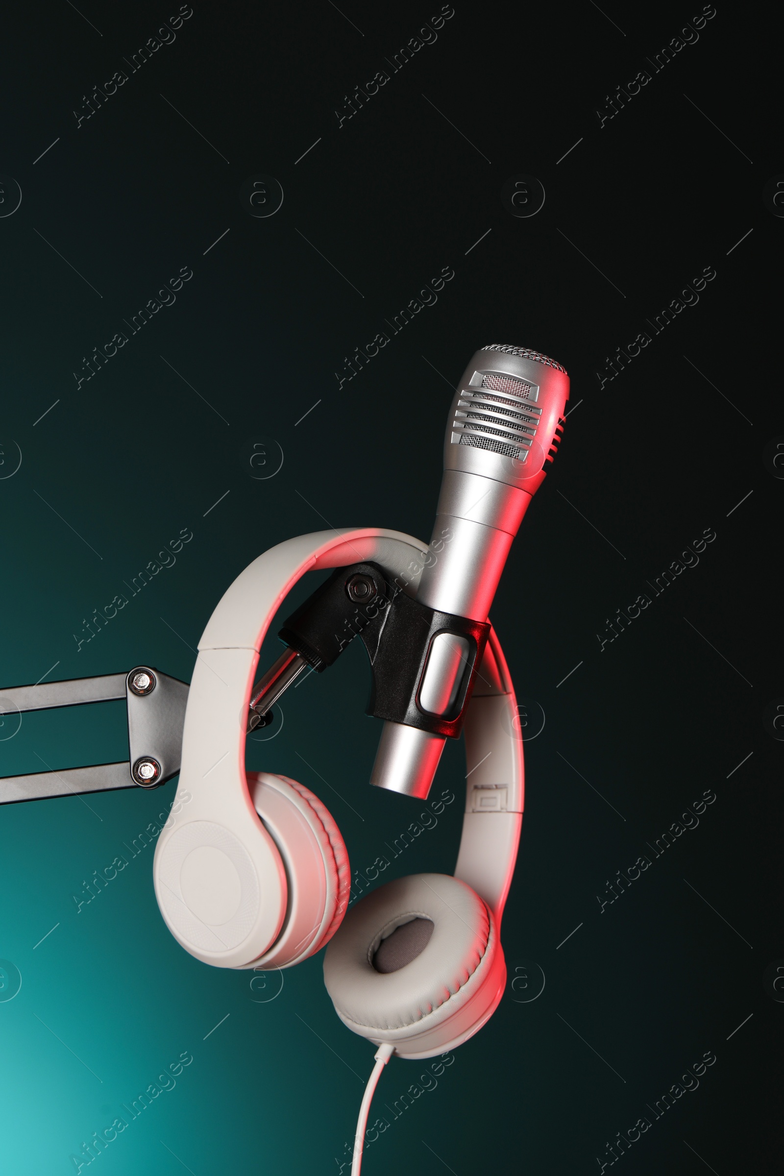 Photo of Stand with microphone and headphones on dark background. Sound recording and reinforcement