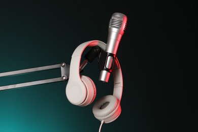 Photo of Stand with microphone and headphones on dark background. Sound recording and reinforcement