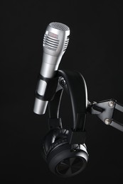 Photo of Stand with microphone and headphones on black background. Sound recording and reinforcement