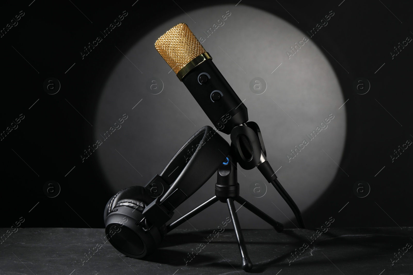 Photo of Stand with microphone and headphones on grey textured table. Sound recording and reinforcement