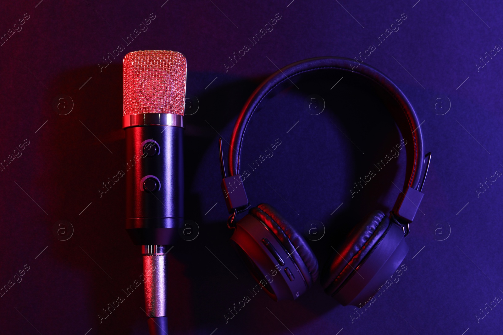 Photo of Microphone and headphones on color background, flat lay. Sound recording and reinforcement