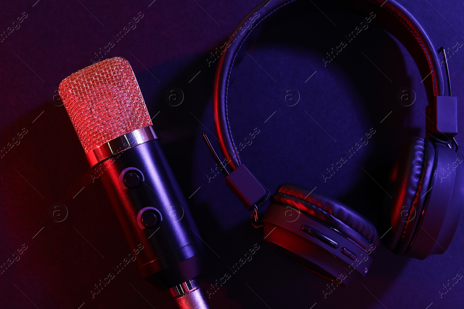 Photo of Microphone and headphones on color background, flat lay. Sound recording and reinforcement