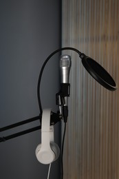 Photo of Stand with microphone, headphones and pop filter indoors. Sound recording and reinforcement