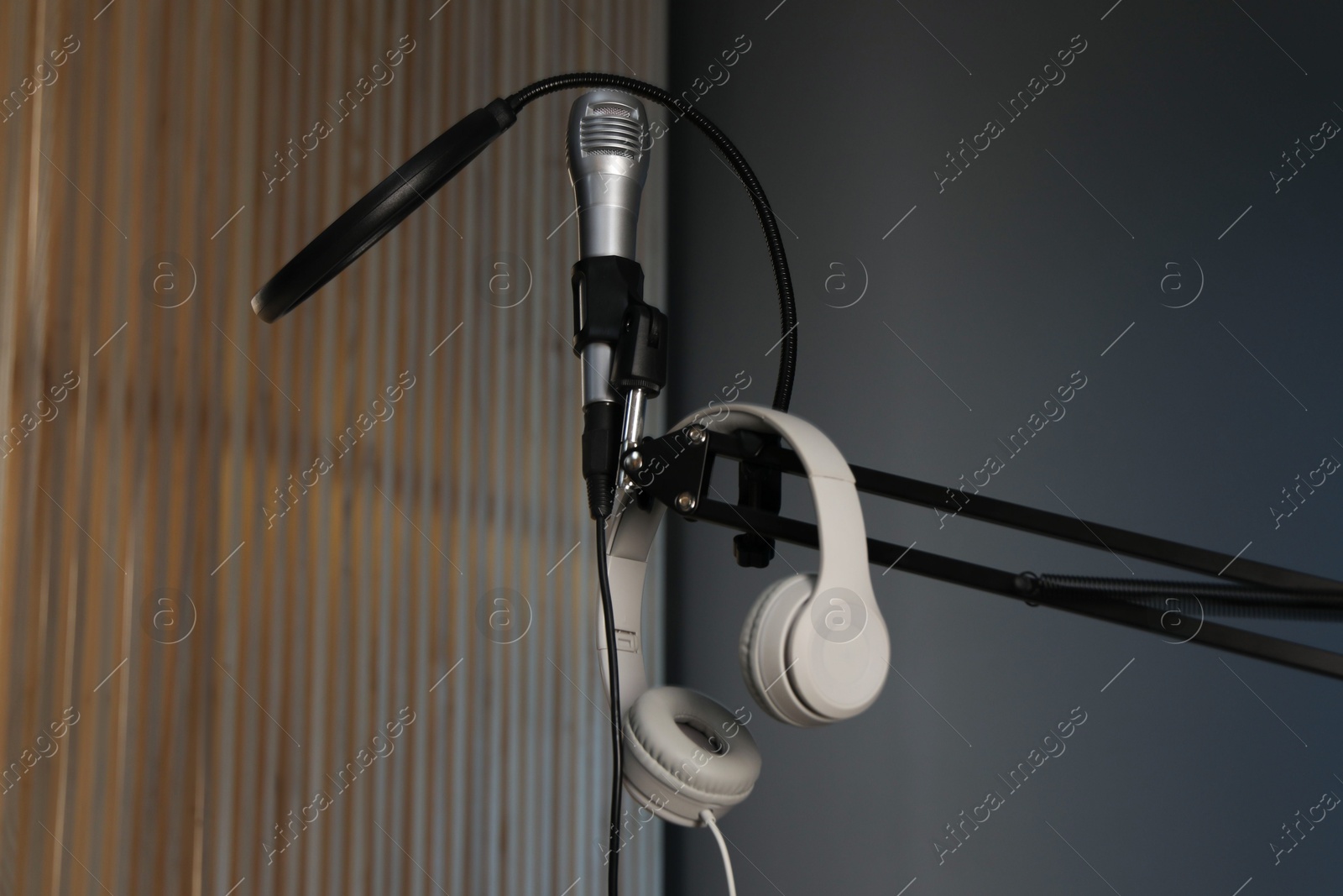 Photo of Stand with microphone, headphones and pop filter indoors. Sound recording and reinforcement