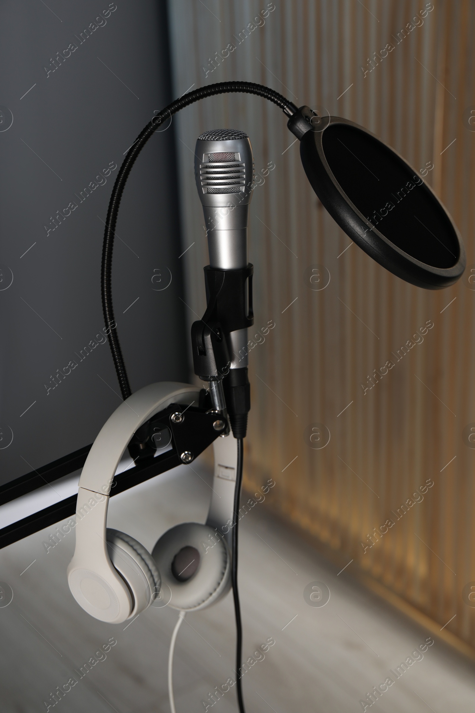 Photo of Stand with microphone, headphones and pop filter indoors. Sound recording and reinforcement