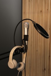 Photo of Stand with microphone, headphones and pop filter indoors. Sound recording and reinforcement