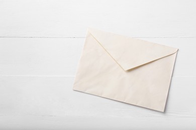 One old letter envelope on white wooden table, top view. Space for text