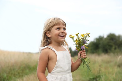 Photo of Cute little girl with flowers at meadow. Child enjoying beautiful nature