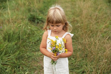 Photo of Cute little girl with flowers at meadow. Child enjoying beautiful nature