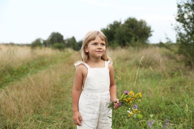 Photo of Cute little girl with flowers at meadow. Child enjoying beautiful nature